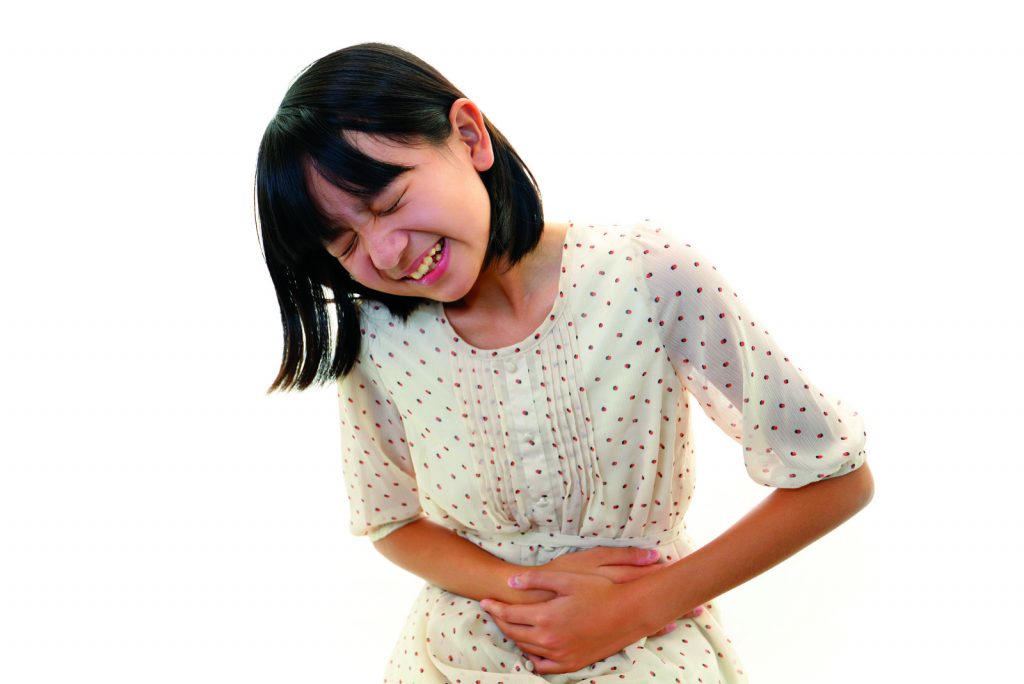 young girl holding her stomach because she is in pain
